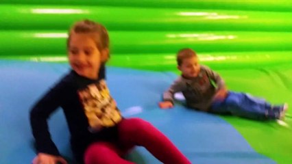 Happy family at indoor playground for kids. They are playing with inflatable toys