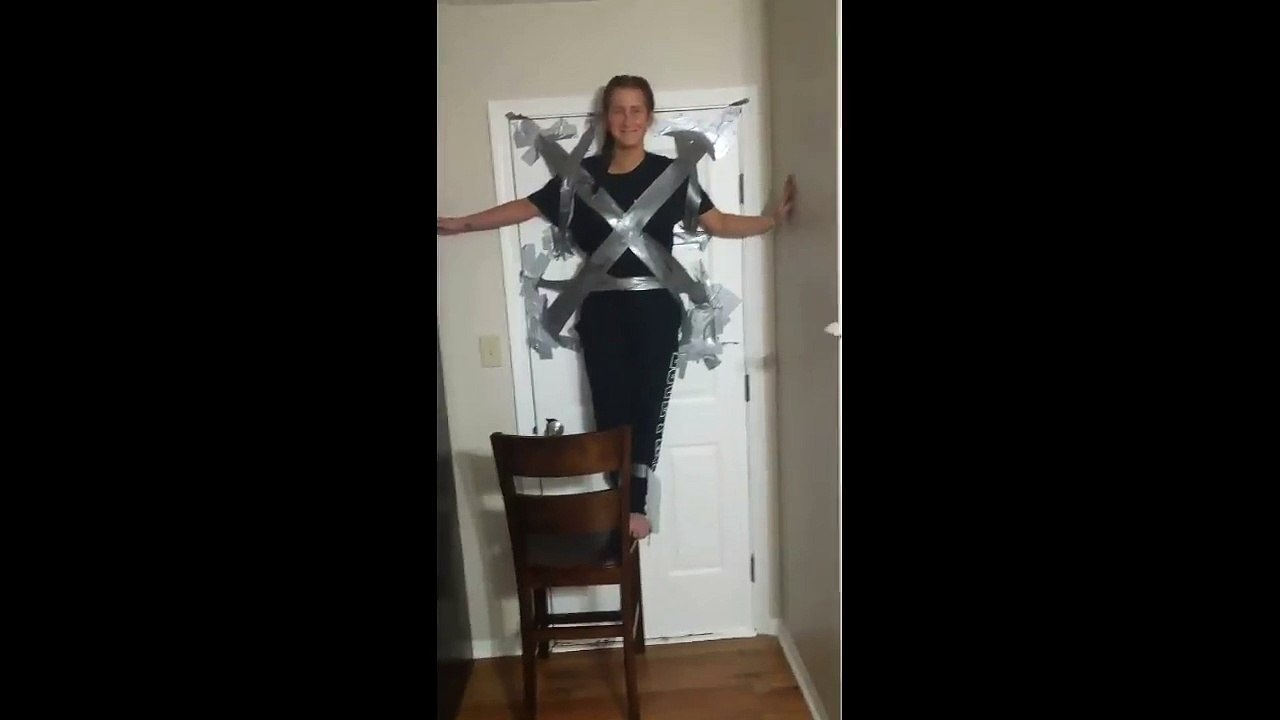 A woman clings herself to a door with duct tape