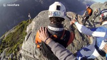 Sheer madness! Daredevils perform headfirst base jump down cliff face