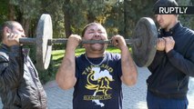 強靭な歯でダンベルを持ち上げるキルギス人男性