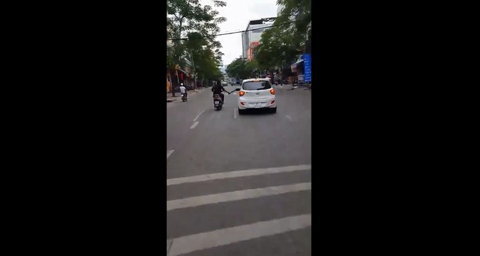 Un scootériste pète un plomb et met des coups de machettes sur les rétroviseurs des voitures.