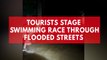 Tourists stage swimming race through flooded street
