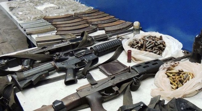 TRAS LAS REJAS TRES SUJESTOS ARMADOS Y VESTIDOS DE MILITARES