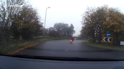 Man falls off moped on wet roundabout