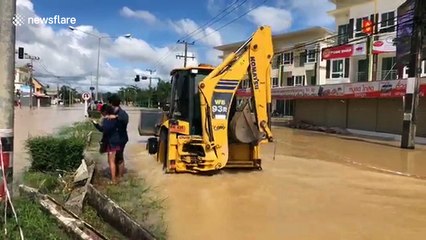 Thai children play on lilos and rubber rings on flooded highway