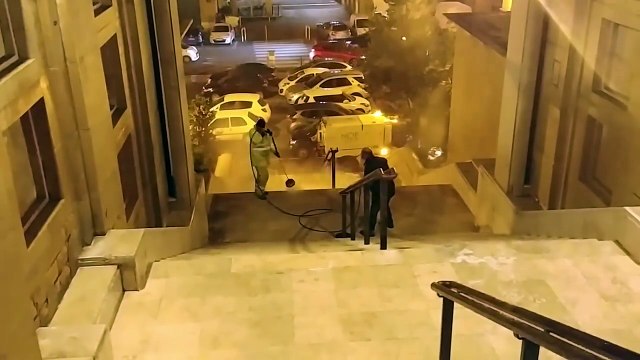 Un employé de la Mairie de Marseille arrose un vieil homme assis sur des escaliers