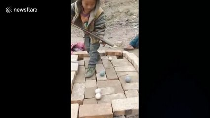 Chinese village children play pool on table made of bricks