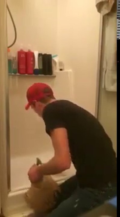 Il essaie de nous montrer comment retirer la touffe de cheveux coincé dans le siphon de la douche