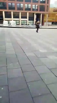 Deux personnes passent au mauvais moment sur une place balayée par le vent