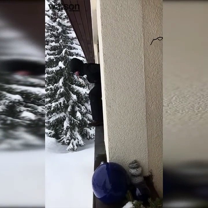 Une femme saute dans la neige depuis le balcon d’un appartement