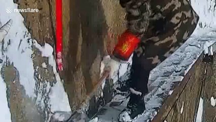 Workers sweep snow off 7000-ft high cliff in China