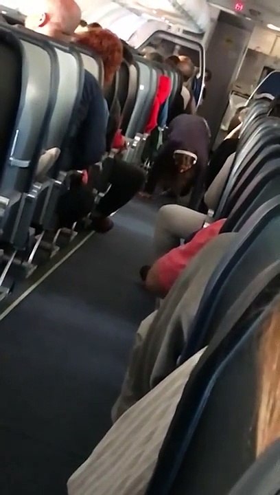 Stressée, une femme fait du Yoga dans le couloir de l’avion
