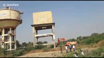 Narrow escape for driver after water tank falls on excavator during demolition