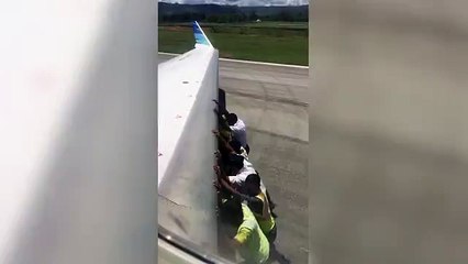 Men push a 35,000kg plane along Indonesian runway