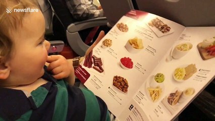 Toddler tries to pick up and eat photos of food from menu
