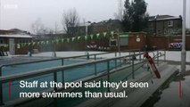 Swimmers take the plunge at an outdoor London lido despite the snowy weather