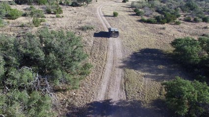 Drone following a military style hummer on a dirt road.