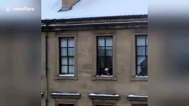Cette vielle jette des boules de neige par la fenêtre sur les gens !