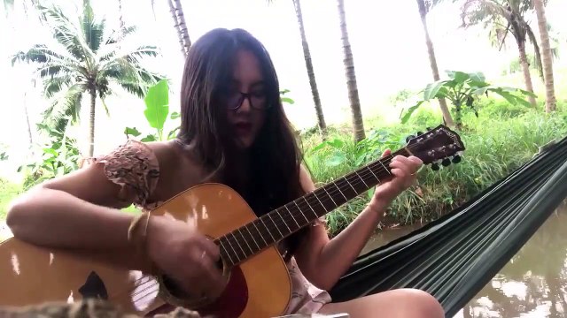 Une fille casse une corde en jouant de la guitare au bord d’une rivière