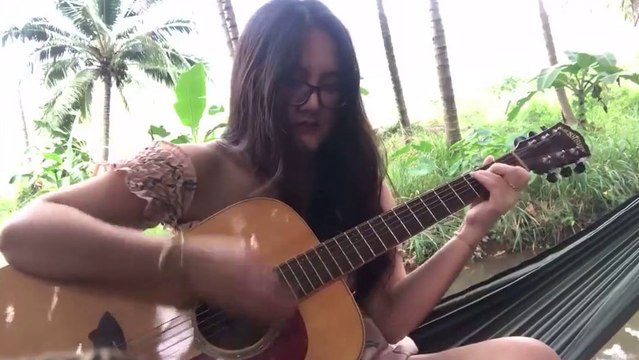 Une fille casse une corde en jouant de la guitare au bord d’une rivière