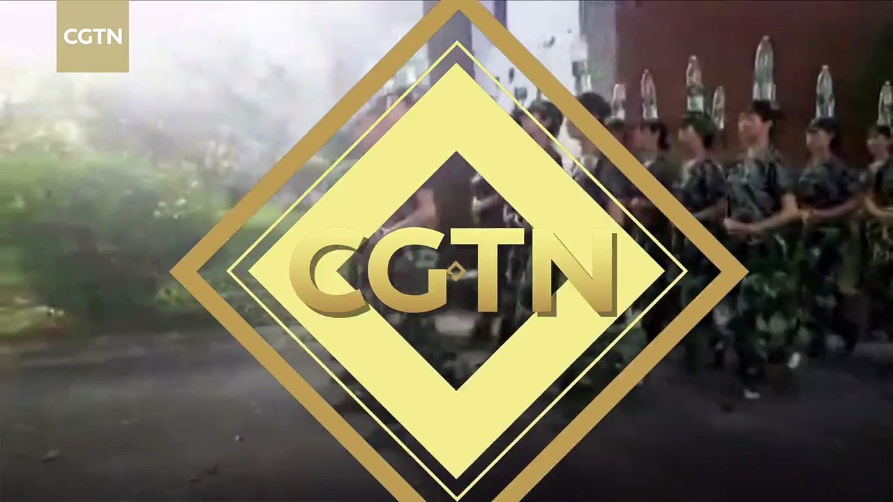 Cadets march while balancing water bottles on their heads