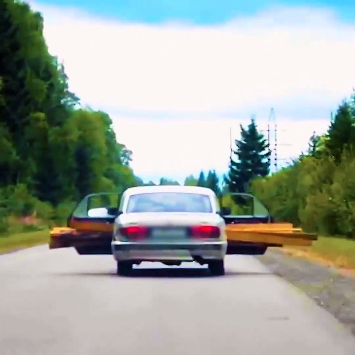 Un automobiliste transporte du bois sur la banquette arrière de sa voiture les portes ouverte.