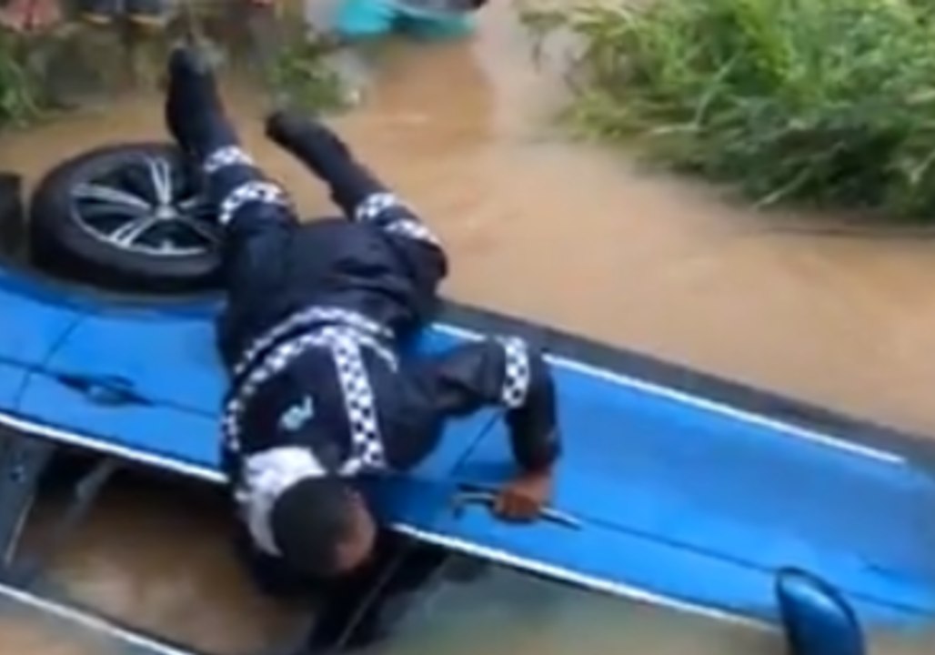 Fijian Police Smash Window of Car Partially Submerged by Floodwaters
