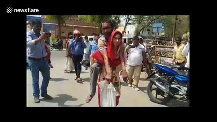 Indian woman carries disabled husband to get him a wheelchair