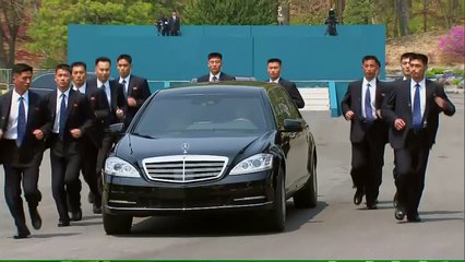 Kim Jong-Un limousine surrounded by jogging security guards