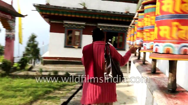Modernity meets Buddhism- Lady speaks on mobile while turning prayer wheels at monastery