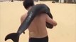 Ce touriste porte un dauphin sur l'épaule à la plage en Chine !