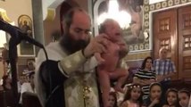 Un prêtre baptise vigoureusement un bébé