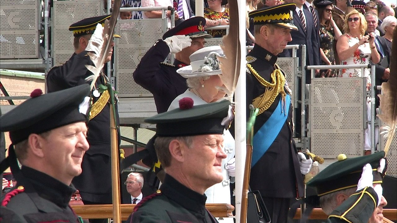 Queen fights strong winds while presenting new flag