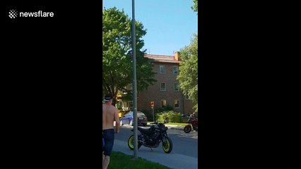 Swedish man juggles while hanging from lamp post