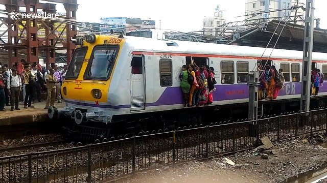 Commuters risk their lives clinging from open doors of packed train in Mumbai
