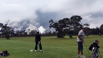 Golfers undistracted by volcano’s massive ash plume behind them