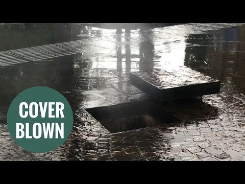Terrifying moment a manhole cover explodes during flash floods