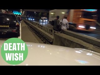 Idiotic couple risk their own lives as they run across the M25 motorway