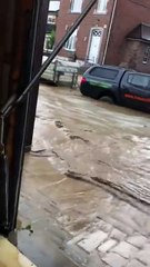 Une femme s’énerve contre une voiture qui passe dans la rue inondée devant chez elle