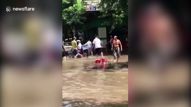 Man ties plastic stools to his feet to cross flooded street