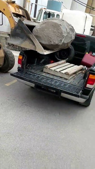 Régis charge un rocher dans un pick-up