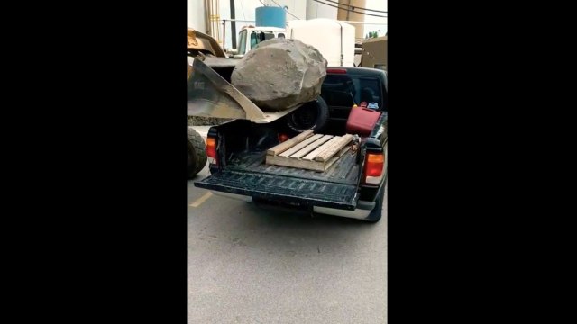 Régis charge un rocher dans un pick-up