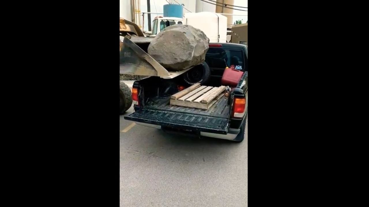 Régis charge un rocher dans un pick-up