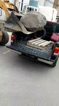 Régis charge un rocher dans un pick-up