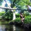 Une femme saute sur un arbre pour se suspendre au dessus d’une rivière