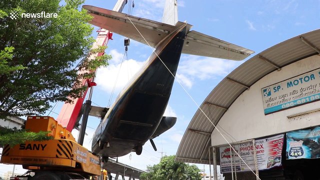 Bizarre moment Vietnam-era war plane is lifted off garage roof