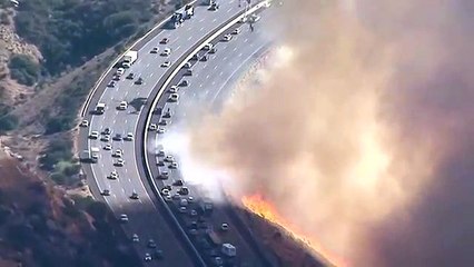 Californie  un hélicoptère largue de leau sur une autoroute au bord des flammes