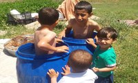 Sıcaktan bunalan çocuklar su dolu varillerde serinliyor
