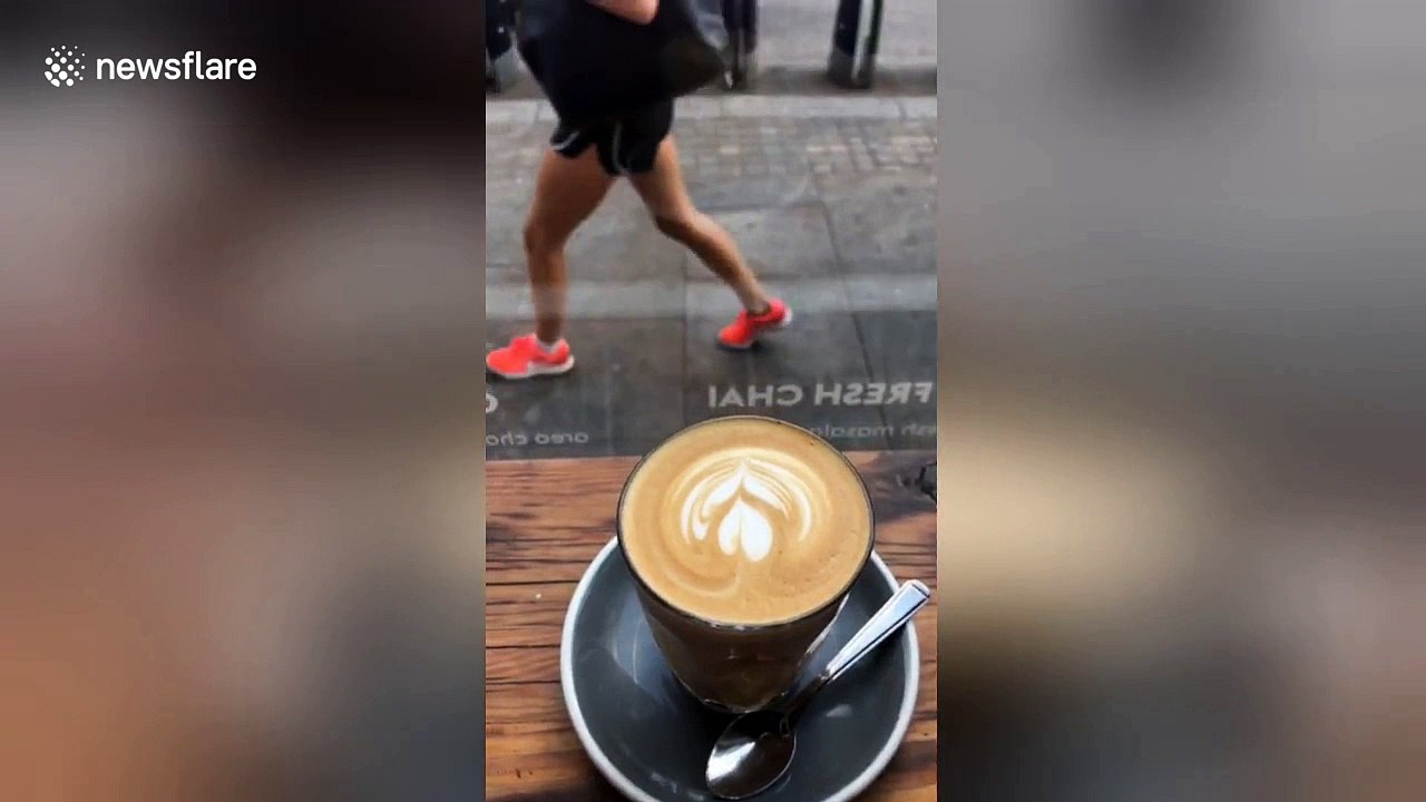 Bare-chested man reclines on chair with drink in middle of London street