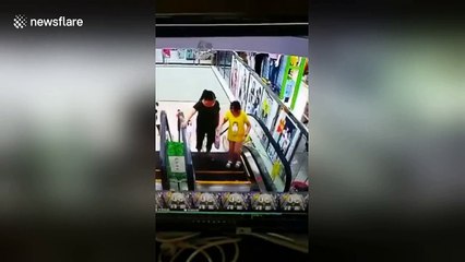 Girl jams head between escalator handrail and wall